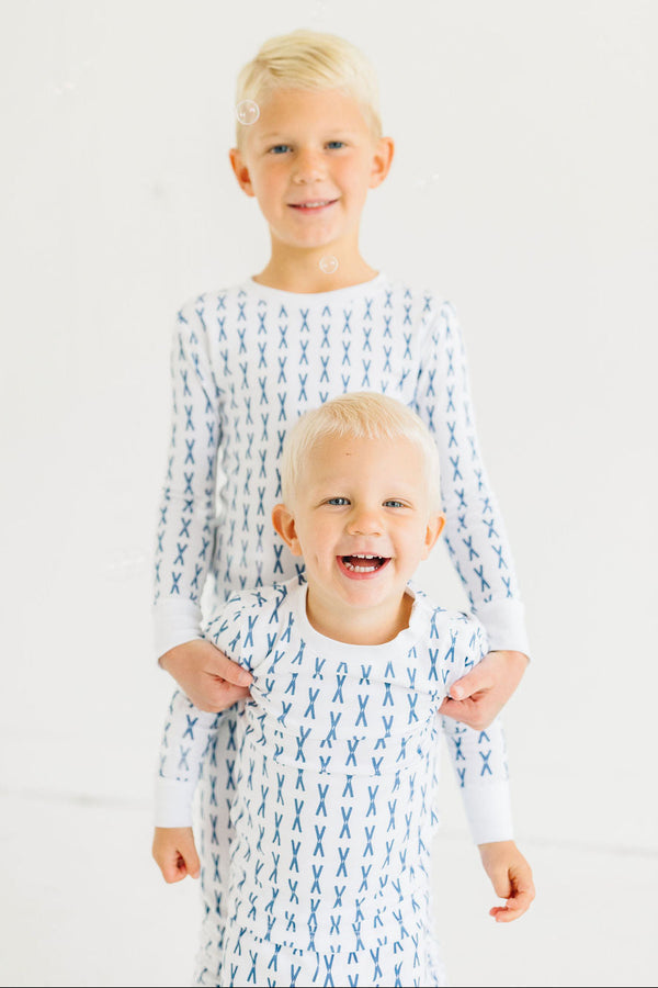 Two children wearing matching pajamas with a blue ski pattern on a white background
